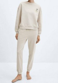 Sudadera beige y joggers a juego hechos de una tela suave. La sudadera cuenta con un pequeño bordado de Mickey Mouse en el pecho. Ajuste cómodo.