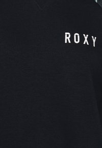 Felpa nera a V in tessuto morbido con il testo bianco "ROXY" sul lato sinistro. Design semplice e senza fronzoli.