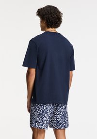 Camiseta de manga corta en azul marino con un corte clásico, combinada con pantalones cortos blancos y azules con un patrón de estrellas de mar.