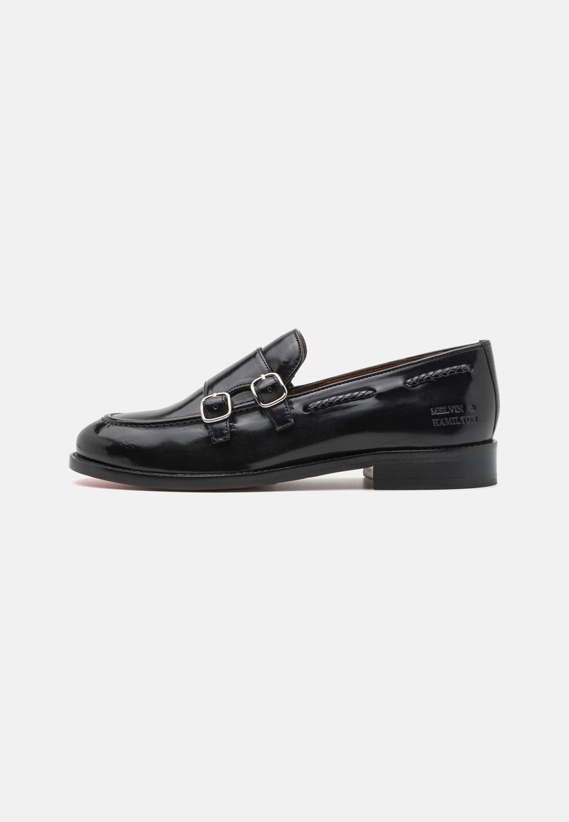 Loafers din piele patent neagră, cu accente dintr-un dublu cataramă argintie, vârf ușor rotund și toc mic, cu straturi. Detaliu de cusătură texturată de-a lungul părții superioare.