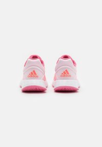 Zapatillas deportivas rosas con un material suave, que cuentan con una suela acolchada, un talón acentuado y una sutil marca en la parte posterior.