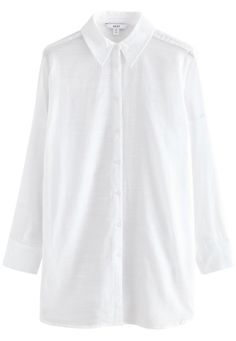 Fehér, gombos ing klasszikus gallérral, hosszú ujjal és struktúrált anyaggal. Egyenes szabású és finom varrásdíszítéssel a vállakon.
