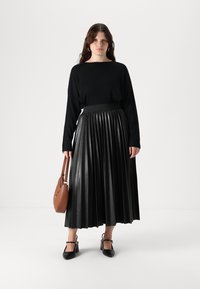 Svart langermet topp, plisserte svarte kunstskinnskjørt, brun handlenett og svarte hæler med ankelremmer. Enkel design og glatt tekstur.