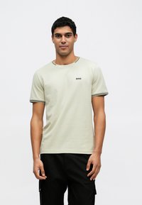 Ανοιχτοπράσινο κοντομάνικο μπλουζάκι με μαύρο περίγραμμα· διαθέτει μικρό λογότυπο "BOSS" στο στήθος· κατασκευασμένο από απαλό ύφασμα.