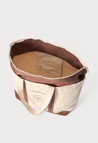 Saco tote de tela com corpo bege e fundo castanho, apresentando duas alças e um bolso com fecho no interior para armazenamento seguro.