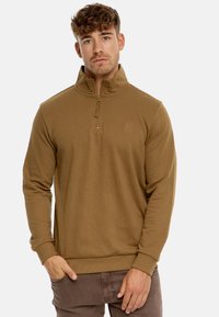 Brun zip-up sweatshirt med høj krave, lavet af blødt stof. Har ribbede manchetter og kant, samt et lille logo på brystet.