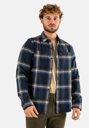 Camisa de cuadro a rayas en material de franela con detalles en blanco y rojo, cierre de botones, dos bolsillos en el pecho y un corte casual.