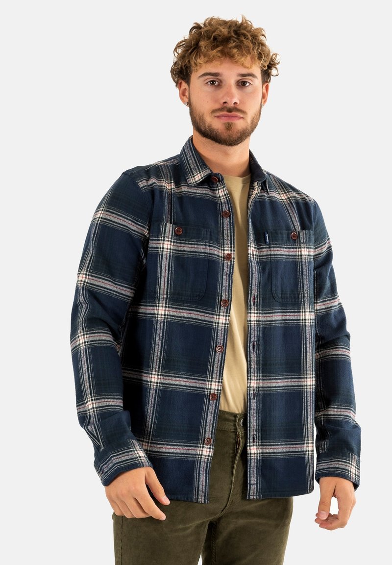 Camisa de cuadro a rayas en material de franela con detalles en blanco y rojo, cierre de botones, dos bolsillos en el pecho y un corte casual.
