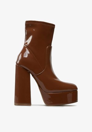 Botín de plataforma de charol marrón con tacón ancho y punta redondeada, con altura media a la pantorrilla y acabado liso y brillante.