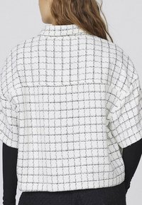 Hvid- og sortternet kortærmet skjorte lavet af tekstureret stof, med krave og en let oversized pasform.