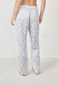 Lichte, pastelkleurige bloemenpyjamabroek met een elastische tailleband. Kenmerkt een blauw bloemenpatroon op een licht crèmekleurige achtergrond. Rechte pijpen.