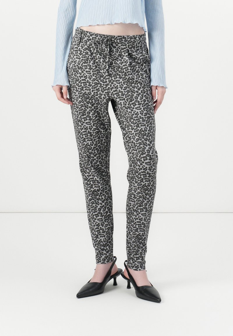 Gryte leopardmønstrede bukser med elastisk liv, snor-lukking og slim fit. Kombinert med svarte spisse hæler.