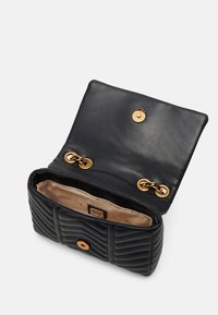 Black leather handbag with quilted texture, gold hardware accents, and a snap closure. Interior shows beige lining with brand logo.