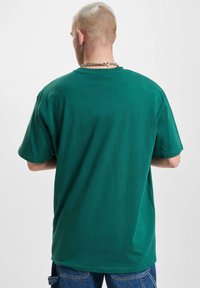 Grøn kortærmet t-shirt lavet af bomuld med en afslappet pasform, der har en klassisk rund halsudskæring og en glat, ensartet tekstur.