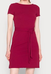 Angeschnittenes, kurzärmeliges Kleid in tiefem Bordeaux mit Rundhalsausschnitt und einem gebundenen Gürtel in der Taille. Weicher, glatter Stoff mit einem dezenten Stretch.