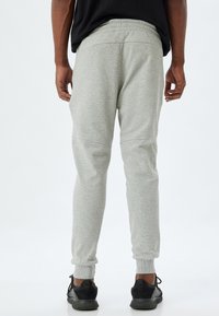 Grå bomullssweatpants med tapered passform, elastisk midja och ribbade ärmslut; har sidoseamsdetaljer och en slät textur.