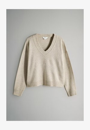 Beige V-hals trui gemaakt van zacht materiaal met verlaagde schouders en ribbelstructuur op de kraag en zoom, met een cropped ontwerp.