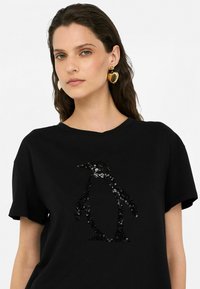 Zwarte katoenen T-shirt met een pinguïnontwerp van pailletten. Ronde halslijn met korte mouwen, gladde textuur, minimalistische stijl.