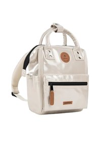 Metallic beige backpack with dual handles, adjustable straps, front zip pocket, and leather logo patch. Features smooth texture and sleek design.