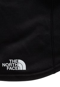 Črno tekstilno gradivo z gladko teksturo, na spodnjem kotu z belo polkrožno zasnovo logotipa "The North Face".