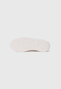 Weiße Sneaker-Sohle mit strukturiertem Muster, das kreisförmige und Zickzack-Profil hat, glatte Kanten und Branding auf der Ferse.