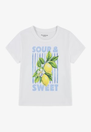 Biała bawełniana koszulka z kolorową grafiką cytryny, zielonymi liśćmi i napisem "SOUR & SWEET" na tle niebieskich pionowych pasków.