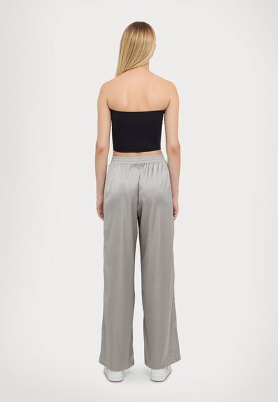 Top noir sans bretelles à coupe ajustée, associé à un pantalon large gris clair avec une taille élastique et une texture lisse.