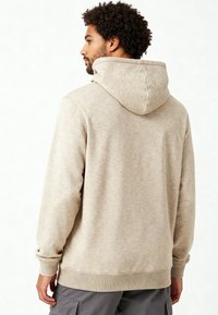 Sweatshirt à capuche beige avec une texture douce, des poignets et un ourlet côtelés, et une coupe décontractée. Dispose d'une capuche centrée à l'arrière et sans graphiques visibles.