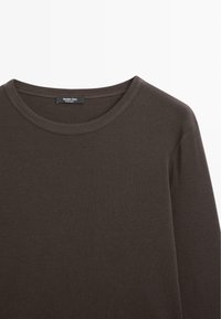 Donkerbruin katoenen T-shirt met lange mouwen en ronde hals, weergegeven met de bovenkant van de voorkant en het label binnenin de kraag tegen een witte achtergrond.
