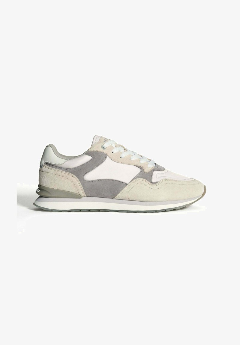 Zapatillas de ante en gris claro y beige, con una mediasuela blanca, detalles texturizados y un diseño de cordones.