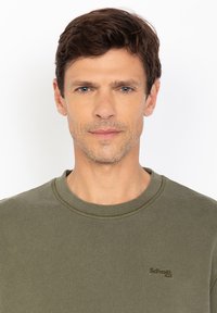 Oliwkowy sweatshirt z prążkowanym dekoltem i subtelnym logo w ciemniejszym odcieniu. Miękka tekstura i swobodny fason.