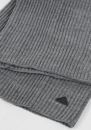 Szary prążkowany szalik wykonany z miękkiego, teksturowanego materiału dzianego. Na krawędzi znajduje się trójkątna czarna metka z logo.