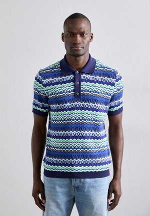 Polo din bumbac de culoare albastră, cu modele în zigzag în verde, bleumarin și bej, mâneci scurte, margine ribbată și deschidere cu trei nasturi.