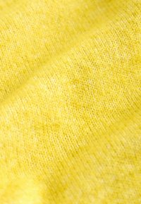 Svijetlo žuta pletena tkanina sa mekanom teksturom; ima glatki, ujednačeni uzorak i blagu varijaciju nijanse.