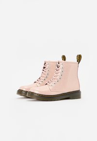 Botas de tobillo rosa brillantes con cordones, material sintético suave, punta redondeada, suela negra en contraste y tiradores amarillos.