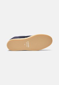 Mornarske slip-on cipele sa mekim tekstilnim gornjim dijelom, s teksturiranom gumenom potplatom i bež šavovima duž ruba. "SCAROSSO MADE IN ITALY" otisnuto.