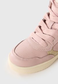 Rosa lädersneaker med perforerat tåhölje, tjocka snören, texturerade gyllene accenter och en kontrasterande krämfärgad gummisula.