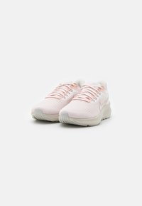 Helle rosa Sport sneakers mit einem strukturierten Mesh-Obermaterial, weißen Schnürsenkeln und einer gepolsterten Sohle. Seitliches Logodesign vorhanden.