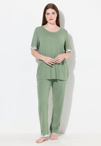 Groene pyjama set van zachte stof met een ronde halslijn, korte mouwen met kantafwerking en bijpassende lange broek met kantdetails aan de zoom.