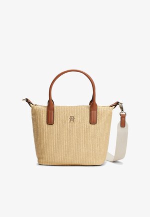 Beige geweven handtas met bruine leren handvatten, een afneembare witte stoffen schouderriem en een klein metalen logo aan de voorkant in het midden.