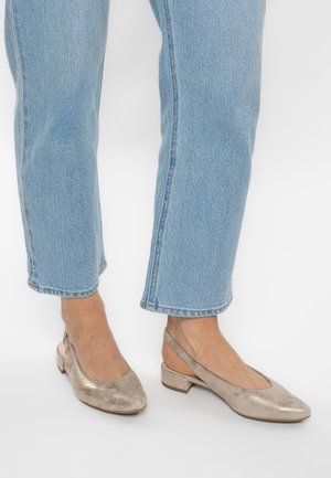 Slingback-Schuhe aus metallisch goldenem Leder mit spitzer Zehenpartie und niedrigem Blockabsatz. Kombiniert mit hellblauen, gekürzten Denim-Jeans.