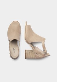Sandales à talons ouvertes beige avec une tige en maille texturée, sangle réglable et un talon épais strié. Accents en cuir lisse.