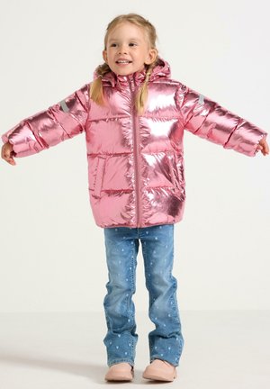 Giacca a vento lucida di colore rosa con cappuccio, dotata di chiusura con zip e polsini elastici. Jeans con piccoli motivi a cuore blu e scarpe di colore chiaro.
