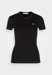 Černé žebrované tričko s krátkým rukávem z bavlny, s malým zeleným logem Lacoste na levé části hrudi. Klasický design s kulatým výstřihem.