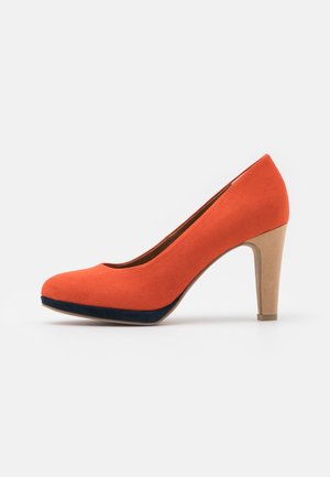 Orange suede high-heeled pump with a rounded toe, featuring a navy blue accent on the front and a beige, textured heel.