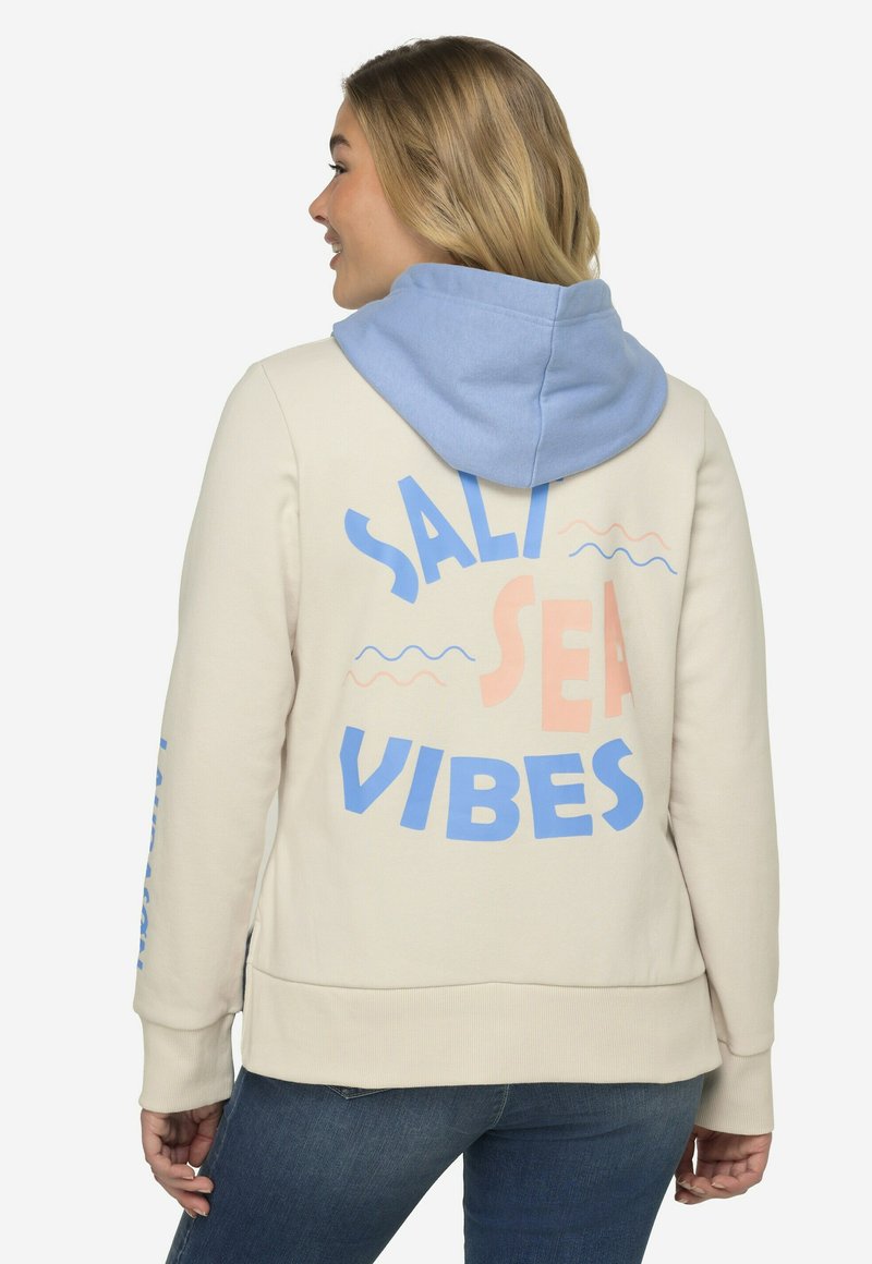 Cremefarvet hættekjole med blå og koralfarvede prints, der siger "SALTY SEA VIBES." Har en lys blå hætte samt ribbede manchetter og kant. Glat tekstur.