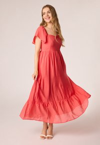 Koraal maxi-jurk met korte, fladderende mouwen, een aansluitende taille en een uitlopende, gelaagde zoom. Gemaakt van een lichtgewicht stof met een gestructureerde uitstraling.