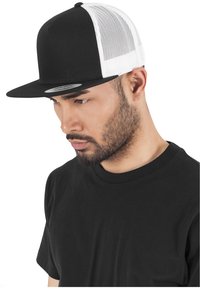 Fekete-fehér trucker sapka, amelynek elülső része teljesen fekete, míg a hátsó része fehér hálós anyagból készült. Lapos csúcsú, árnyékolós; minta vagy díszítés nélkül.
