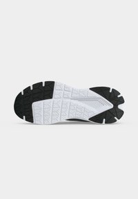 Semelle d'une chaussure de sport noire et blanche avec des motifs texturés conçus pour la traction et la durabilité.