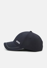 Tengerészkék baseball sapka pamutkeverékből, fehér varrással és hímzett 'BOSS' logóval az elején. Ívelt karimával és szellős szellőzőkkel.